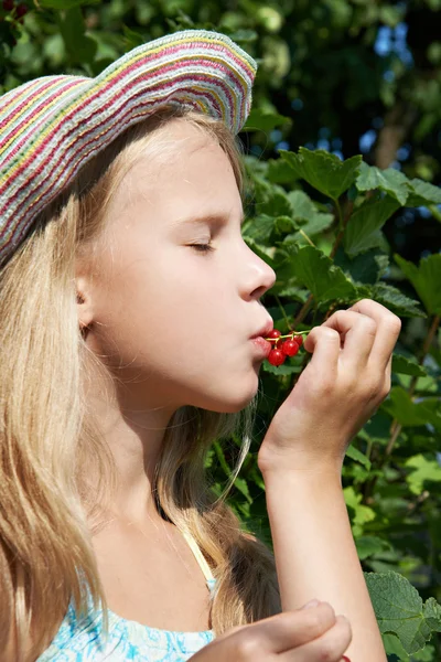 Menina come groselha vermelha no jardim — Fotografia de Stock