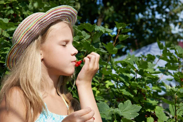 Dziewczyna zjada Czerwona porzeczka w ogrodzie — Zdjęcie stockowe