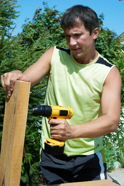 Человек сверлит деревянную доску — стоковое фото