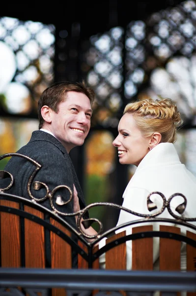 Happy bride and groom on decorative bench — Stock Photo, Image