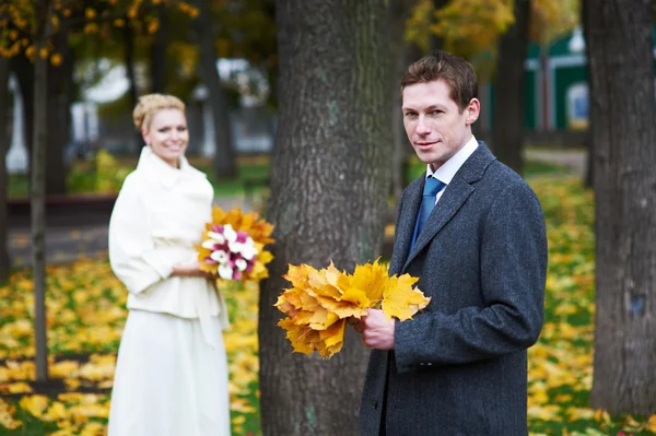 Bride and groom with yellow maple leaf — Stock Photo, Image