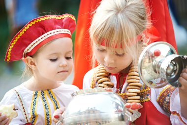 Two girls in Russian national costumes with samovar clipart