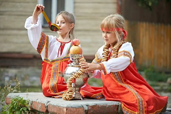 Två flickor i ryska nationella kostymer med samovar — Stockfoto
