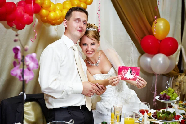 Bride and groom show a greeting card — Stock Photo, Image