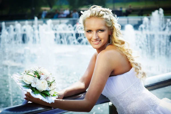 Happy bride with bouquet of flower near fountain — Stock Photo, Image