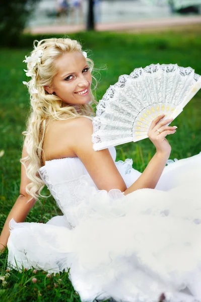 Happy bride with fan on grass — Stock Photo, Image