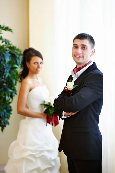 Happy bride and groom near bright window — Stock Photo, Image