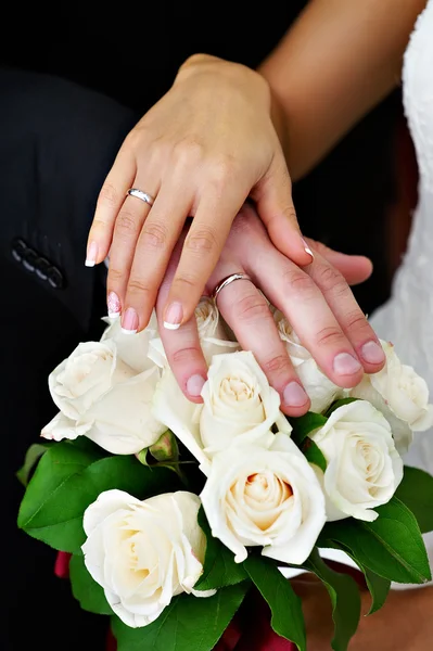 Mãos com ouro de casamento e buquê de flores — Fotografia de Stock