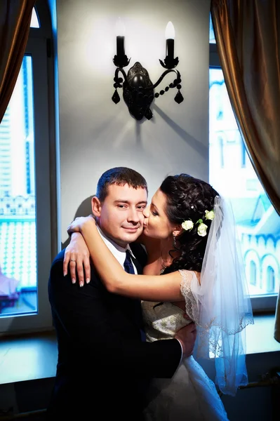 Bela noiva beijando seu noivo na bochecha — Fotografia de Stock