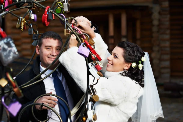 Happy bride and groom near metal tree with symbol lock — Stock Photo, Image