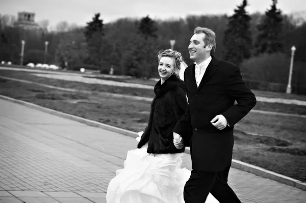 Glückliche Braut und Bräutigam laufen auf Garten — Stockfoto
