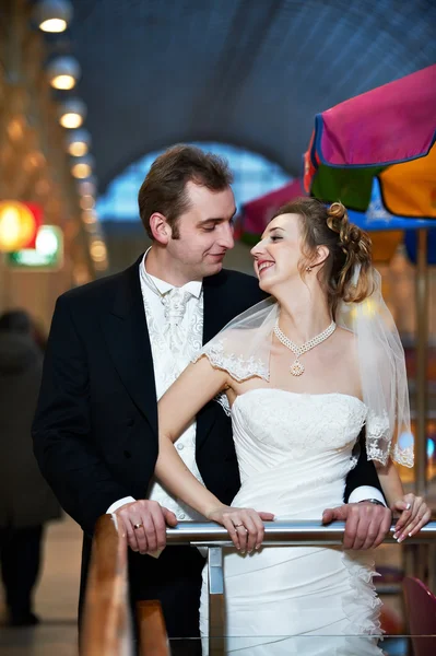 Happy bride and groom in interior of shopping center — Stock Photo, Image