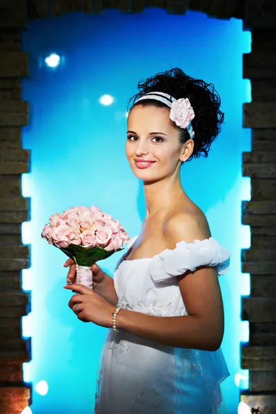 Bela noiva com buquê de flores no fundo azul — Fotografia de Stock