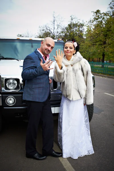 Счастливая невеста и жених возле свадебного лимузина — стоковое фото