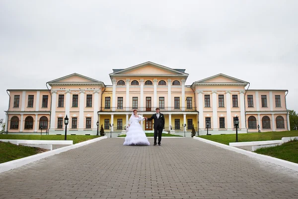 Жених и невеста на свадьбе прогулка возле дворца — стоковое фото