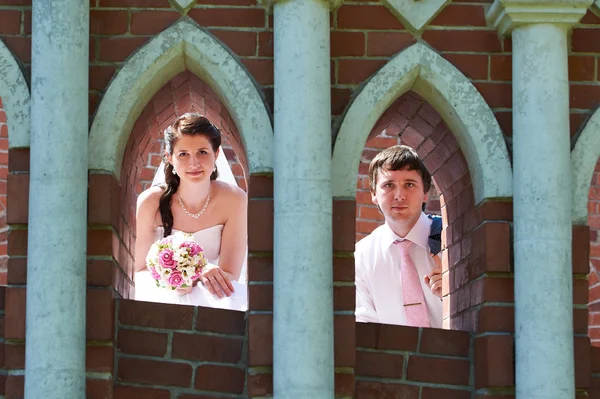 Happy bride and groom in windows of brick wall — Stock Photo, Image