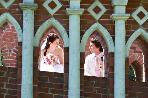 Happy bride and groom in windows of brick wall — Stock Photo, Image