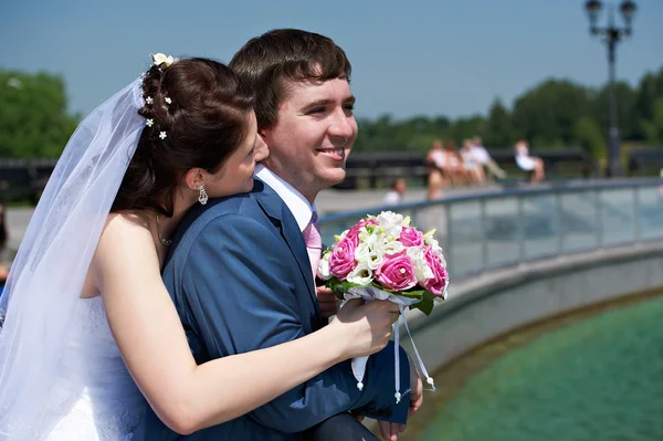 Happy bride and groom with bouquet in park — Stock Photo, Image