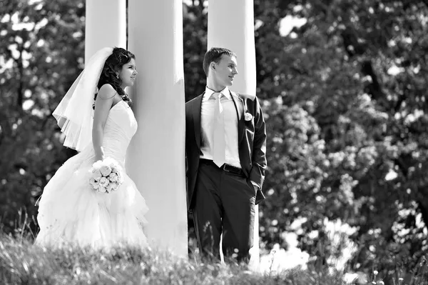 Bride and groom at wedding walk around column — Stock Photo, Image