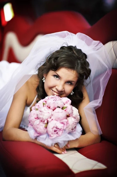 Happy bride with wedding bouquet in limo — Stock Photo, Image