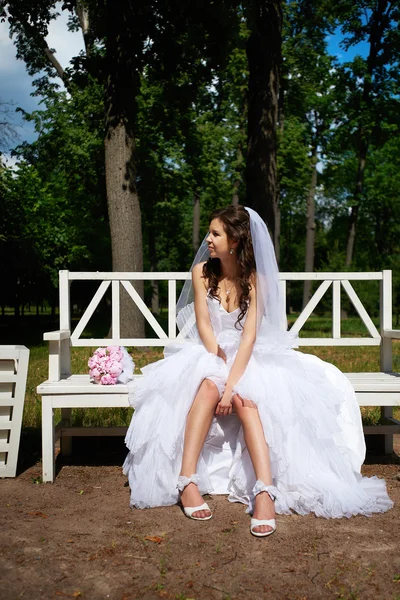 Bride on bench in park — Stock Photo, Image