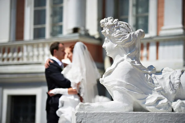 Novia y novio cerca de la escultura de león femenino — Foto de Stock