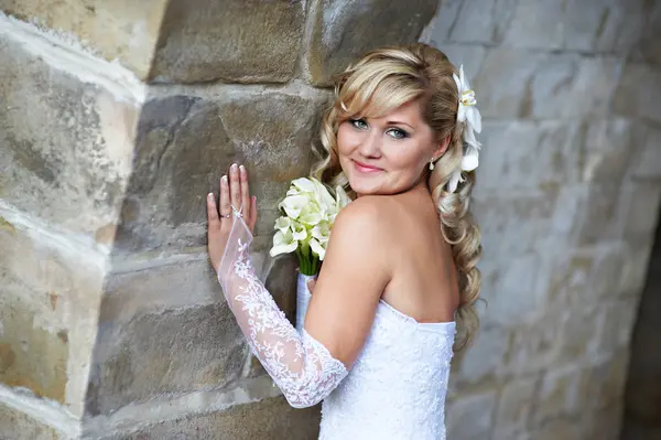 Feliz novia cerca de la pared de piedra — Foto de Stock