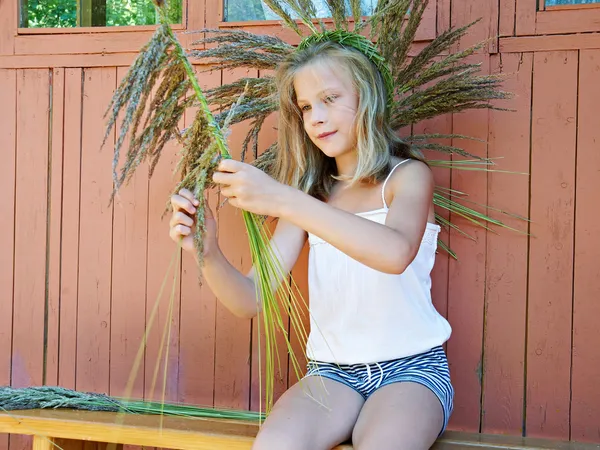 Meisje weeft een krans van gras — Stockfoto