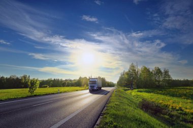 Landscape with a moving truck on the highway at sunset.