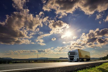 Landscape with a moving truck on the highway at sunset.