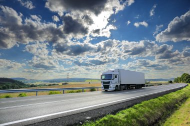 Landscape with a moving truck on the highway at sunset.