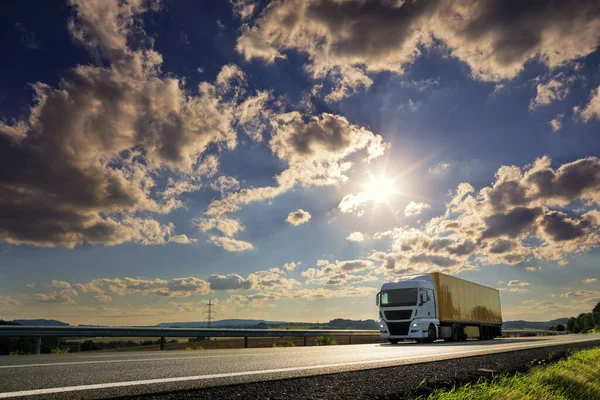 Landscape with a moving truck on the highway at sunset.