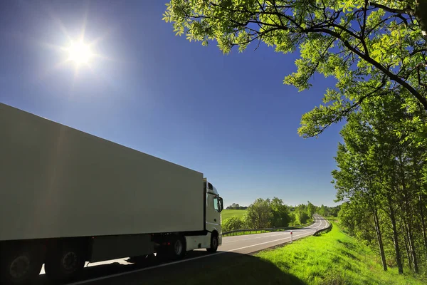 Landscape with a moving truck on the highway at sunset.