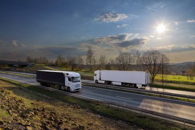 Landscape with a moving truck on the highway at sunset.