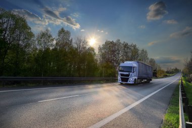 Landscape with a moving truck on the highway at sunset.