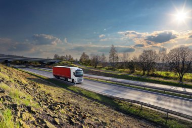 Landscape with a moving truck on the highway at sunset.