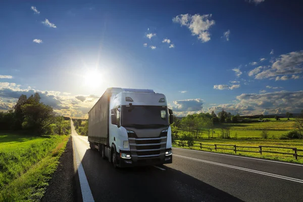 Landscape with a moving truck on the highway at sunset.