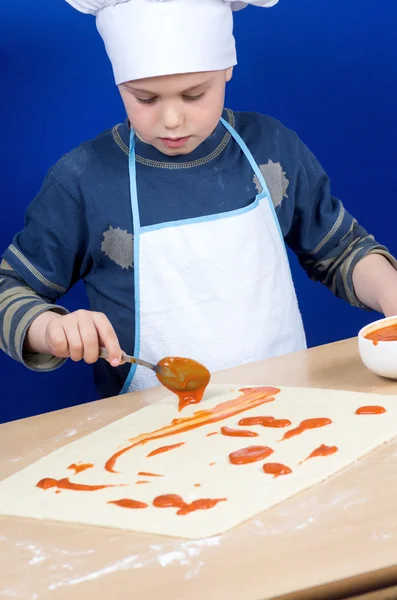 Niño poniendo los ingredientes de la pizza — Foto de Stock