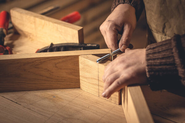 A man makes wood products with the help of special tools. Portrait of a young carpenter at work. Employment in the woodworking industry
