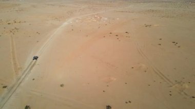 Suudi Arabistan çölünde uluslararası ralli etkinliğini yürüten bir yarış arabasının hava görüntüsü