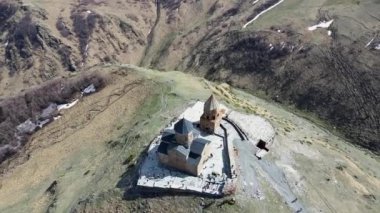 Kamera insansız hava aracı etrafta uçuyor ve Gürcistan 'ın Stepantsminda kasabası yakınlarındaki Kutsal Üçleme Kilisesi' ne (Gergeti Trinity Kilisesi) iniyor.