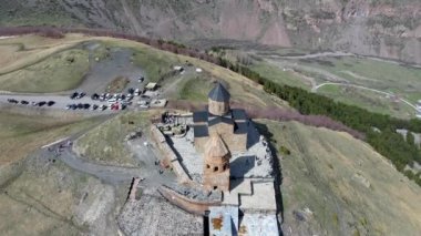 Gürcistan 'ın Stepantsminda köyü yakınlarındaki Kutsal Üçleme Kilisesi' nin (Gergeti Trinity Kilisesi) üzerinde kameralı hava aracı uçuyor ve yükseliyor.