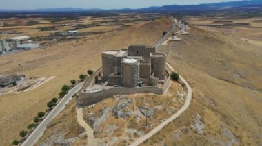 A camera drone ascends over iconic Consuegra Castle (Spanish: Castillo de Consuegra) and windmills, La Mancha