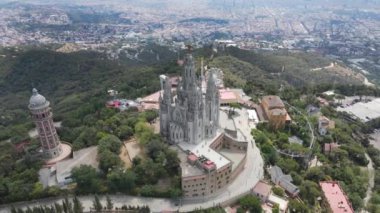 A camera drone flies around the Temple of the Sacred Heart of Jesus and Tower of the Waters of Two Rivers, Barcelona, Spain