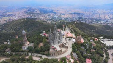 A camera drone flies forward above the Temple of the Sacred Heart of Jesus and Tower of the Waters of Two Rivers, Barcelona, Spain