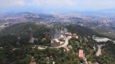 A camera drone flies forward above the Temple of the Sacred Heart of Jesus and Tower of the Waters of Two Rivers, Barcelona, Spain