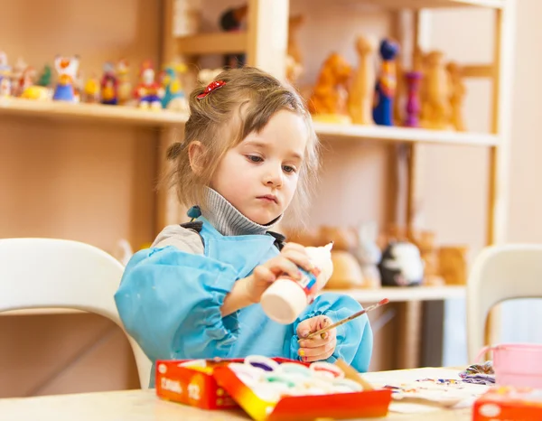 Liten flicka med sax och lim i skolan — Stockfoto