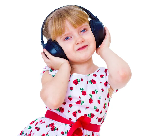 Charming little girl loves to listen to music through headphones — Stock Photo, Image