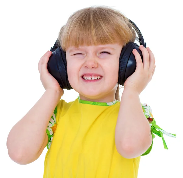 Charming little girl loves to listen to music through headphones — Stock Photo, Image