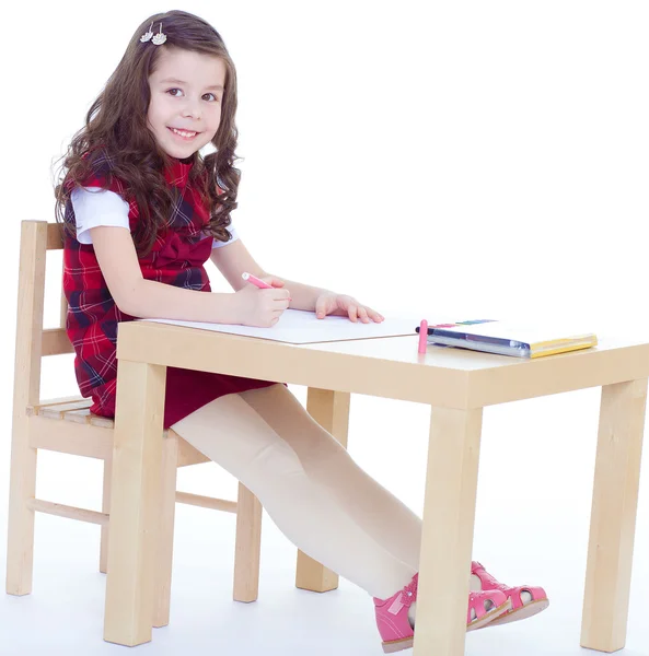 小さな女の子が描画色の鉛筆を使用してテーブルに座っている間 — ストック写真